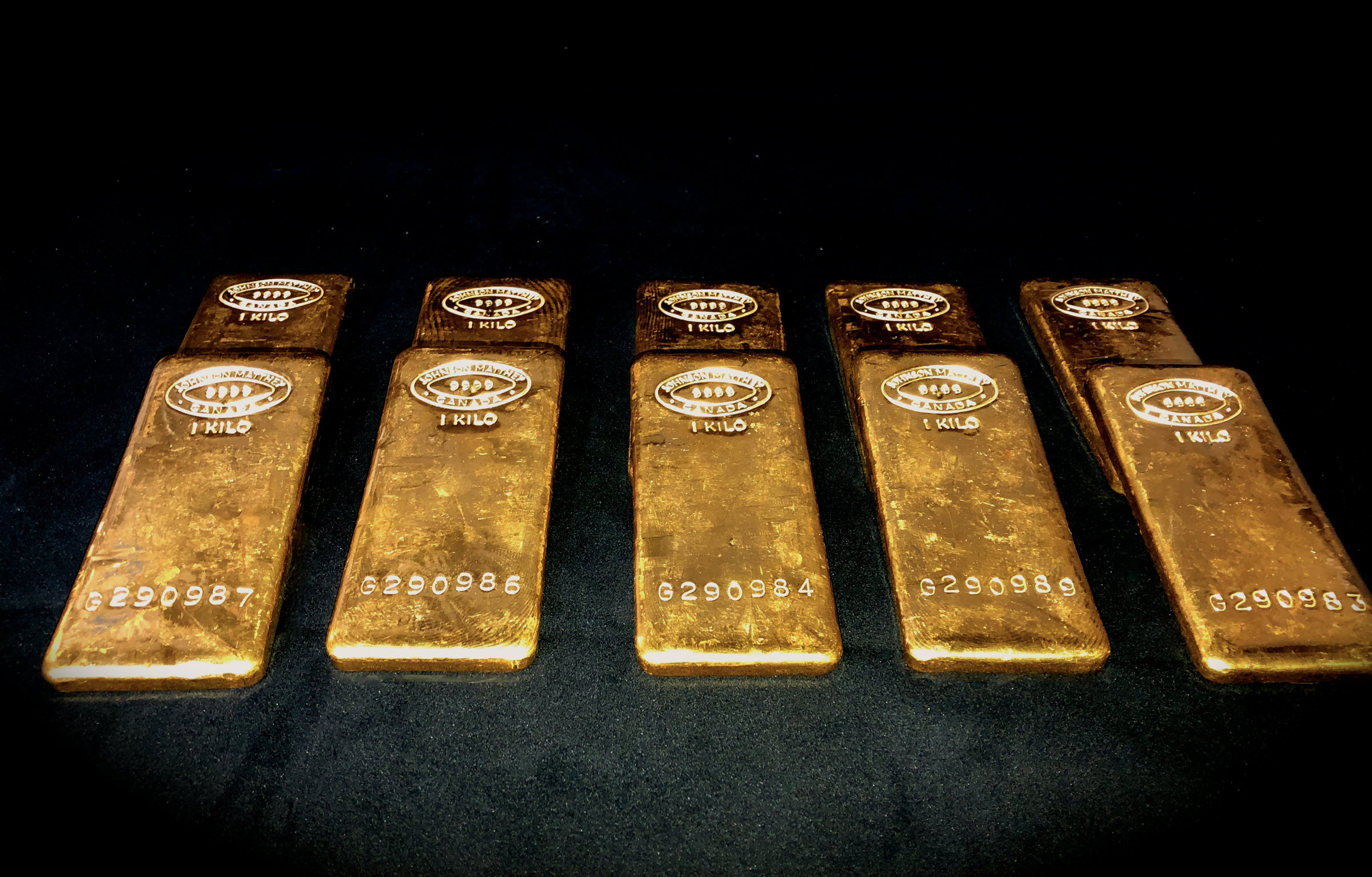 10 Gold Johnson Matthey bars on a black background within a vault 10 Gold Johnson Matthey bars on a black background within a vault