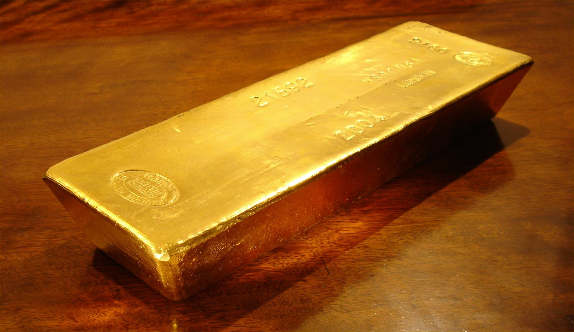 Gold bar on polished wooden table Gold bar on polished wooden table